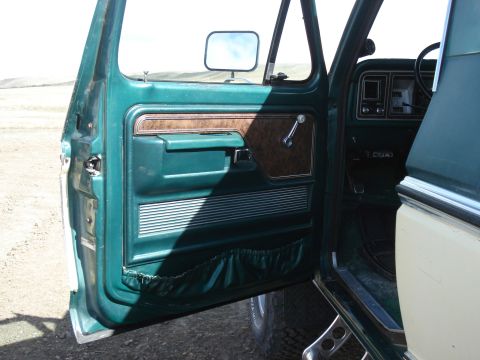 1979 Ford Bronco - The interior of a 1979 Ford Bronco, showing the green door panel and dashboard details.