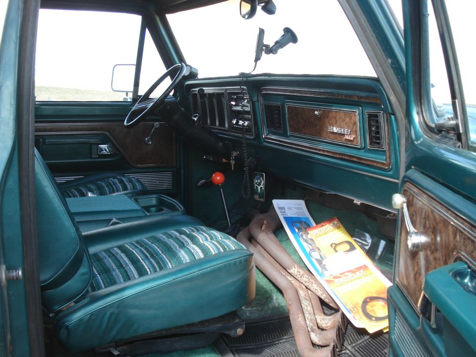 Interior of a 1979 Ford Bronco showing green seats, dashboard, and wood trim