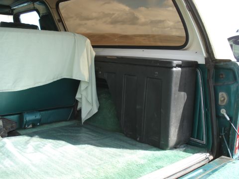 1979 Ford Bronco - The interior cargo area of a 1979 Ford Bronco features green carpeting and a large black storage container.