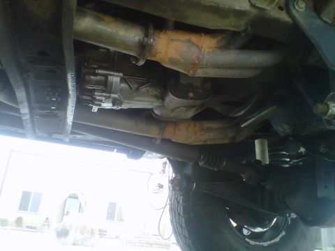 1994 Ford F-150 - A view of the undercarriage of a vehicle, revealing its mechanical components and a tire.