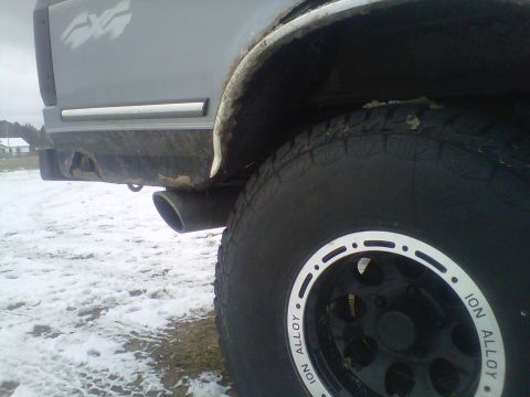 1994 Ford F-150 - A gray truck's rear side is shown with a prominent off-road tire and wheel in the foreground.