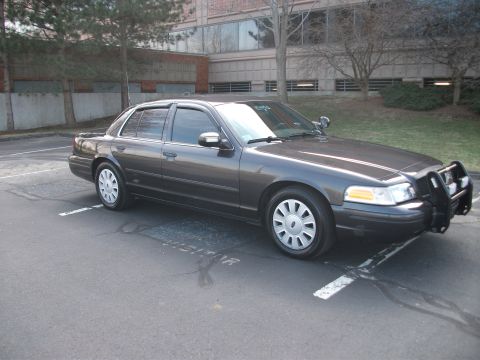 2001 Ford Crown Victoria - Dark gray 2001 Ford Crown Victoria police car with a push bumper is parked in a lot.