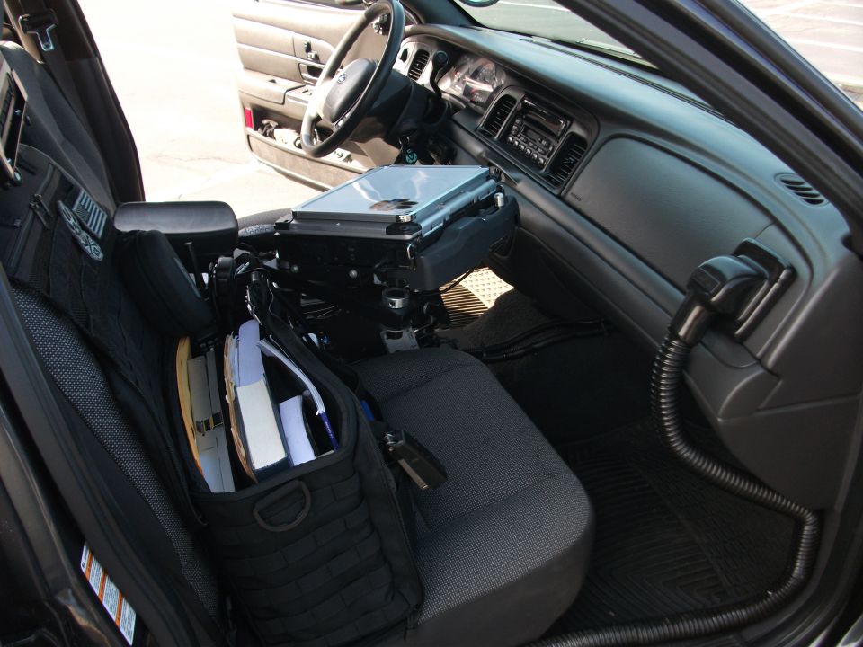 Interior of a 2001 Ford Crown Victoria police car, showing laptop mount and seat organizer