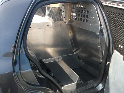 2001 Ford Crown Victoria - The rear interior of a vehicle has been modified with a metal cage and partition, suggesting it's used for law enforcement or security purp…