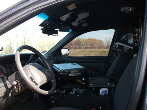 2001 Ford Crown Victoria - The interior of a police vehicle is shown, equipped with a laptop and communication devices.