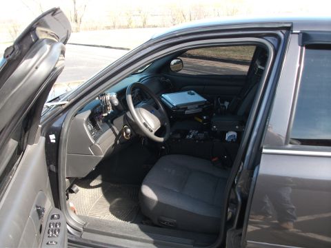 2001 Ford Crown Victoria - Interior view of a dark gray 2001 Ford Crown Victoria, equipped with a laptop mount and police equipment.