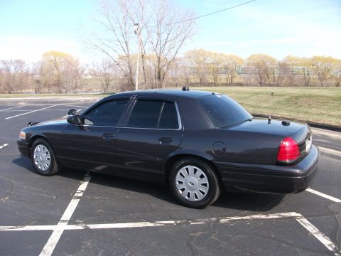 2001 Ford Crown Victoria - This sedan is parked in a lot with trees and a building in the background.