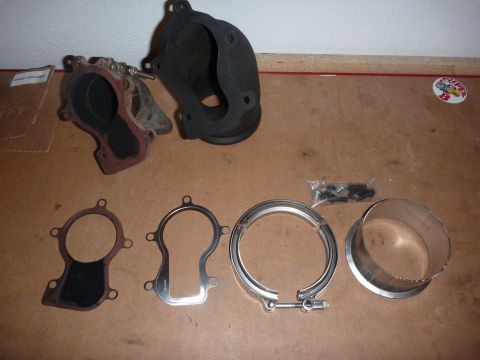 1997 Dodge 2500 - Various turbocharger components are laid out on a workbench, including a metal adapter and exhaust housing.