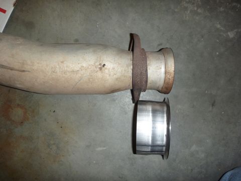 1997 Dodge 2500 - A close-up view of an exhaust pipe section with a flange, next to a separate metal ring, resting on a concrete surface.