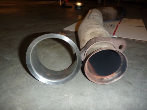 1997 Dodge 2500 - Exhaust pipe and flange shown with a separate metal ring on a concrete floor.