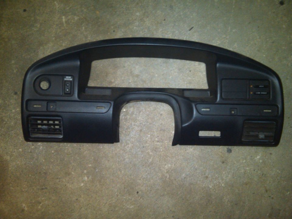 Black plastic dashboard trim piece with vents and switch openings