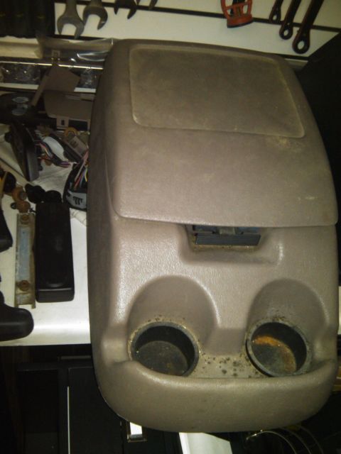 1993 Ford Bronco - This is a tan center console with two cup holders and an air vent, likely from a vehicle's interior.