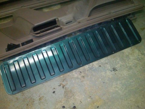 1993 Ford Bronco - A green metallic trim piece with raised ribs is shown next to a car door panel.