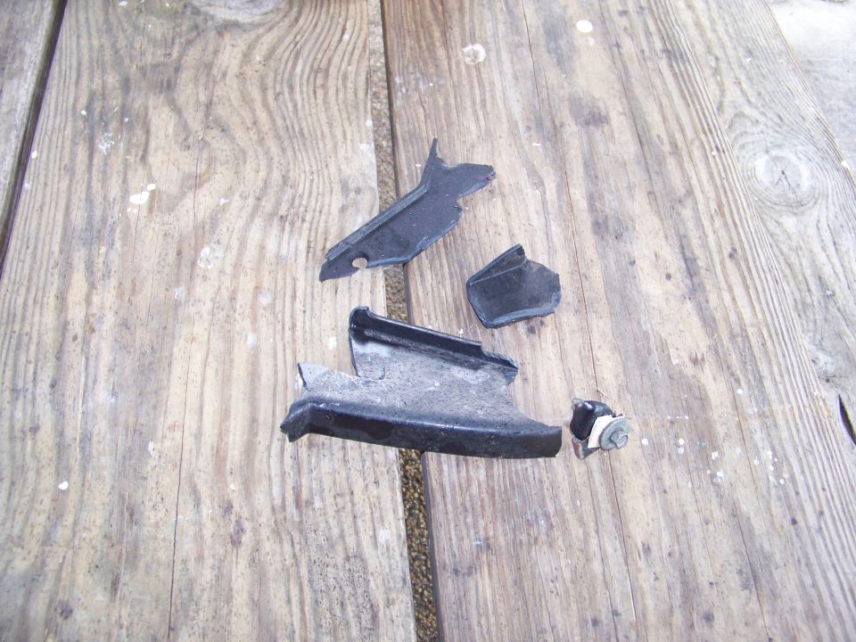 Broken black plastic car parts on a wooden surface