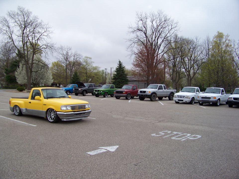 Yellow lowered Ford Ranger in front of a line of other Ford Rangers parked in a lot