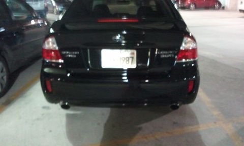 2008 Subaru Legacy - The rear of a black sedan is shown, with a license plate that reads '1987'.