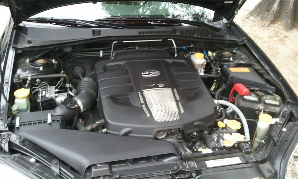 Black engine bay of a 2008 Subaru Legacy, showing the V3 engine cover and various components