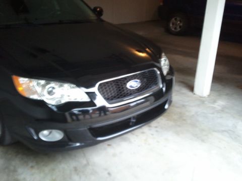 2008 Subaru Legacy - Front view of a black Subaru sedan, parked indoors next to a pillar. Another vehicle is in the background.