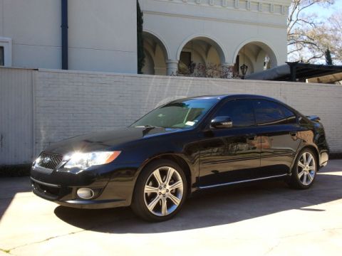 2008 Subaru Legacy - A black sedan is parked outside a building with arched windows, showing its front and side profile.