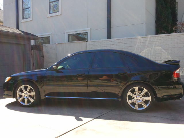 Black sedan parked in driveway. It has tinted windows and a spoiler