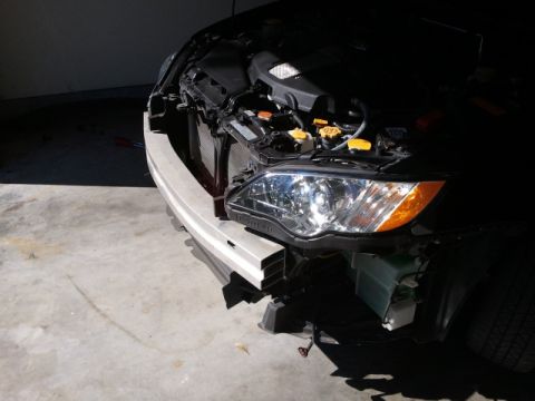 2008 Subaru Legacy - The front of a car is shown with the hood open, revealing the engine and exposed bumper area, suggesting repair or maintenance.