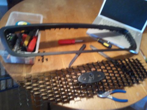 2008 Subaru Legacy - Disassembled car grille with tools and a laptop on a wooden table.