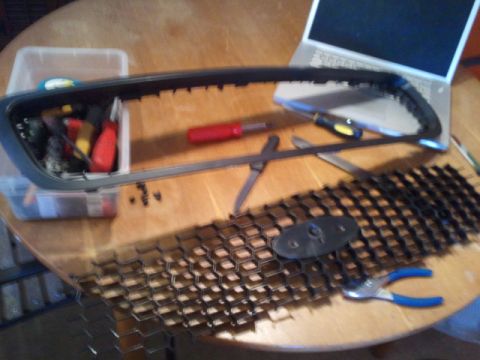 2008 Subaru Legacy - A car grill is laid out on a table with various tools, including screwdrivers and pliers, and a laptop in the background.