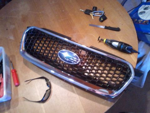 2008 Subaru Legacy - A Subaru grille is laid out on a wooden surface with various tools and a pair of sunglasses nearby.