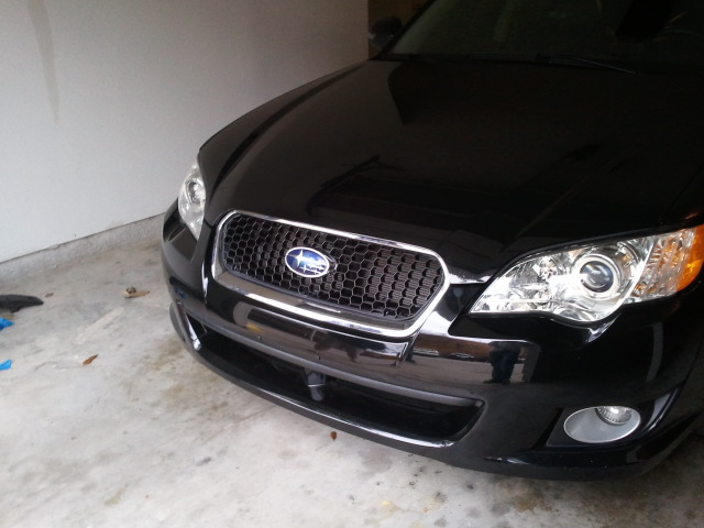 Black Subaru Legacy front grille and headlights, parked indoors