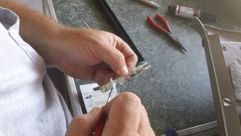 1994 Ford Bronco - Close-up of hands repairing a car interior part with tools nearby.