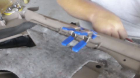 1994 Ford Bronco - Close-up of an interior door panel with blue clips being used for repair, alongside gray carpeted material.