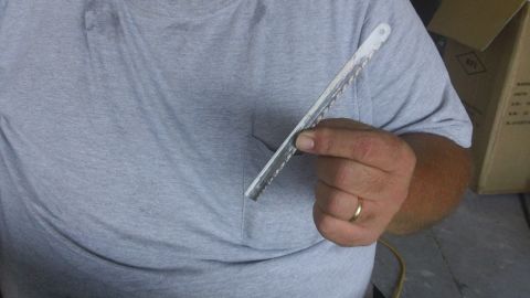 1994 Ford Bronco - A hand holds a jigsaw blade, with a cardboard box in the background.