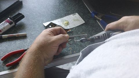 1994 Ford Bronco - Close-up of hands using a rotary tool for detailed work on a small component.