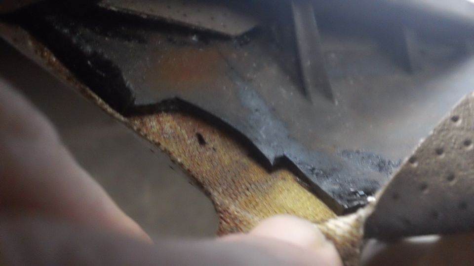 Close-up of a car's interior door panel showing damaged brown fabric and black plastic trim