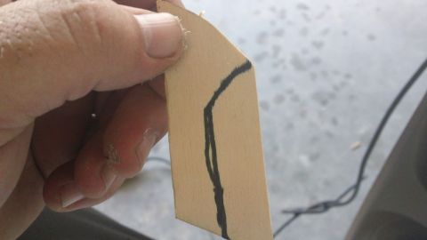 1994 Ford Bronco - A hand holds a piece of cardboard with a black line drawn on it.