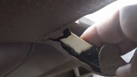 1994 Ford Bronco - A finger is shown pulling at a damaged section of the vehicle's interior trim.