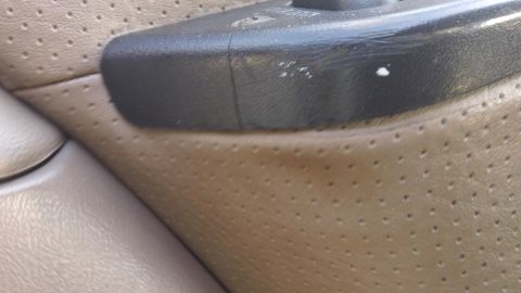 1994 Ford Bronco - Close-up of a vehicle's interior door panel and armrest, showing wear and tear.