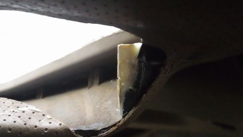 1994 Ford Bronco - This image shows a detail of a vehicle's undercarriage, focusing on a section of trim and adhesive material.