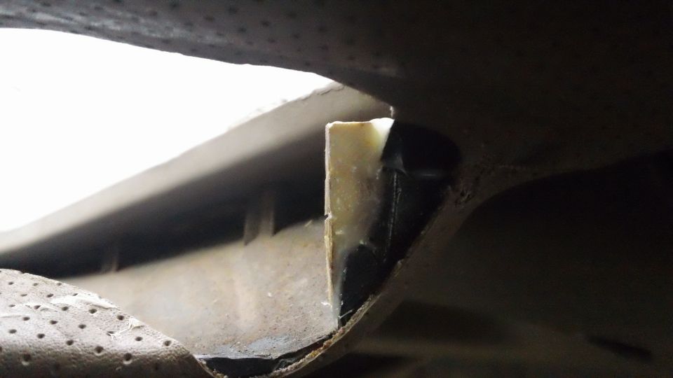 close-up of a vehicle's undercarriage showing a piece of trim and some adhesive