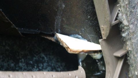 1994 Ford Bronco - A piece of wood is wedged into a damaged interior car panel, obscuring the view of the car's interior.