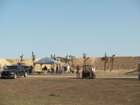 1996 Ford Bronco - A black pickup truck and a red utility vehicle are visible at an outdoor event with people gathered under a tent.