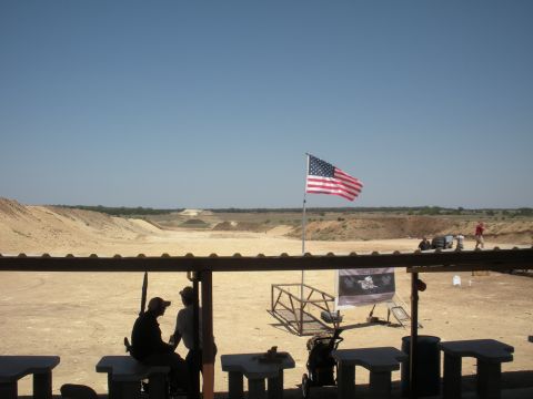1996 Ford Bronco - An American flag waves over a shooting range with people and tables in the foreground.