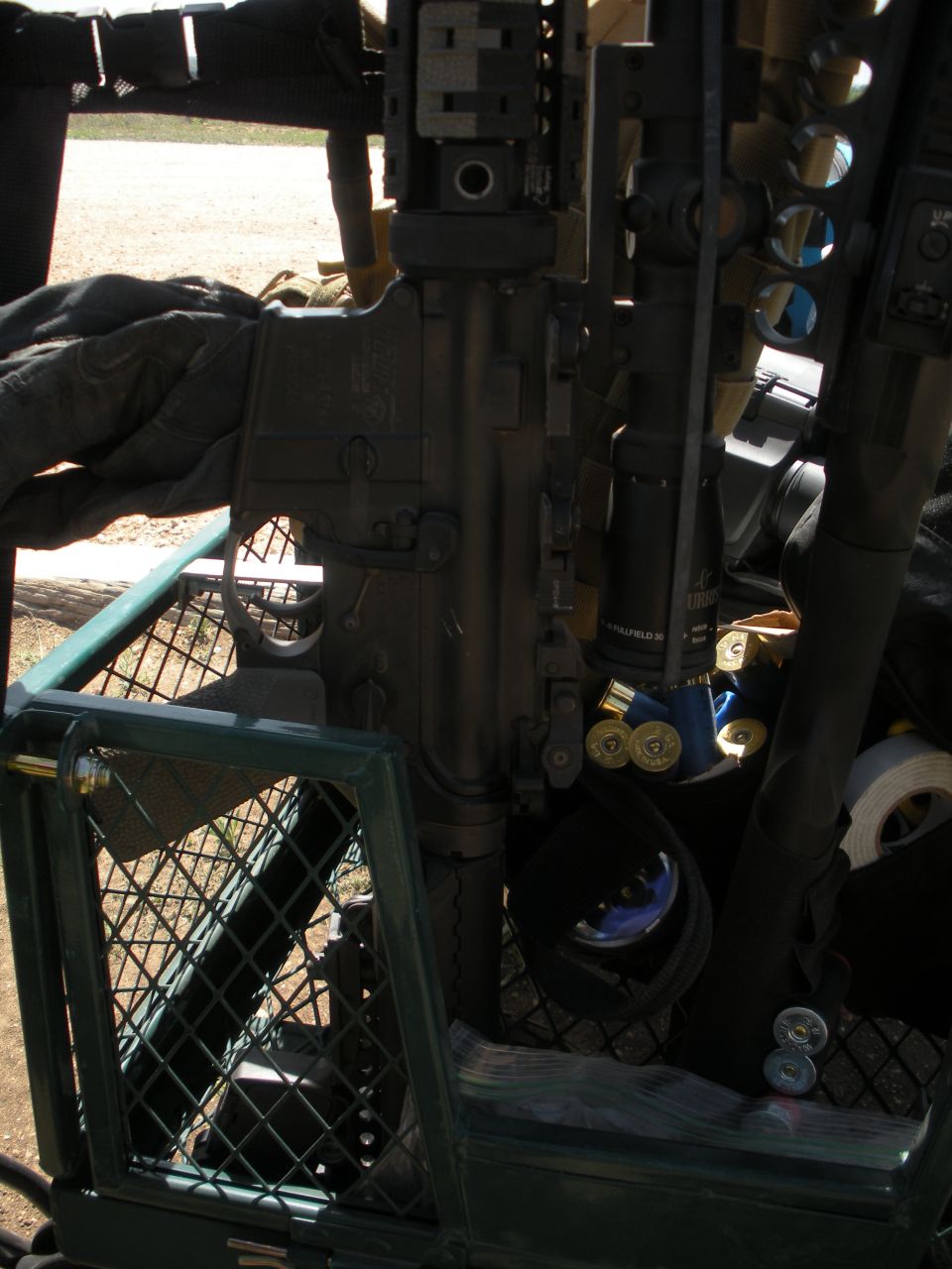 Close-up of a firearm with shotgun shells and other gear in a cage