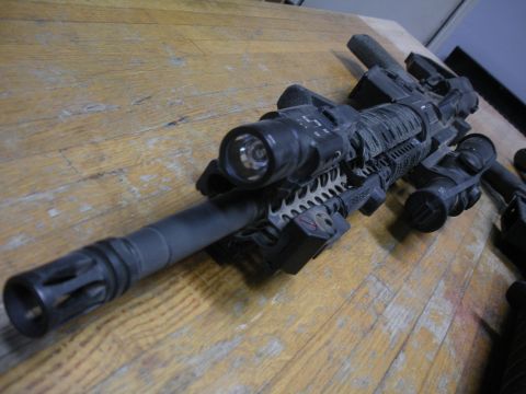 1996 Ford Bronco - Tactical rifle with multiple accessories attached, resting on a wooden table.
