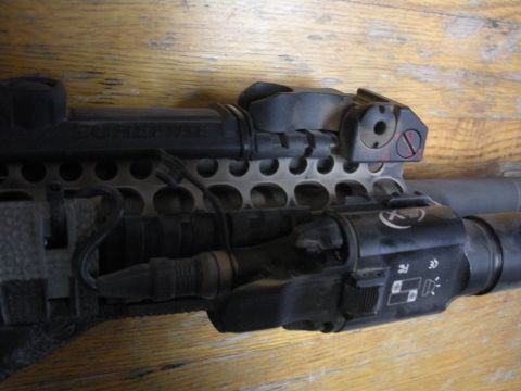1996 Ford Bronco - Close-up view of a tactical flashlight attached to a rail system, showing various markings and controls.
