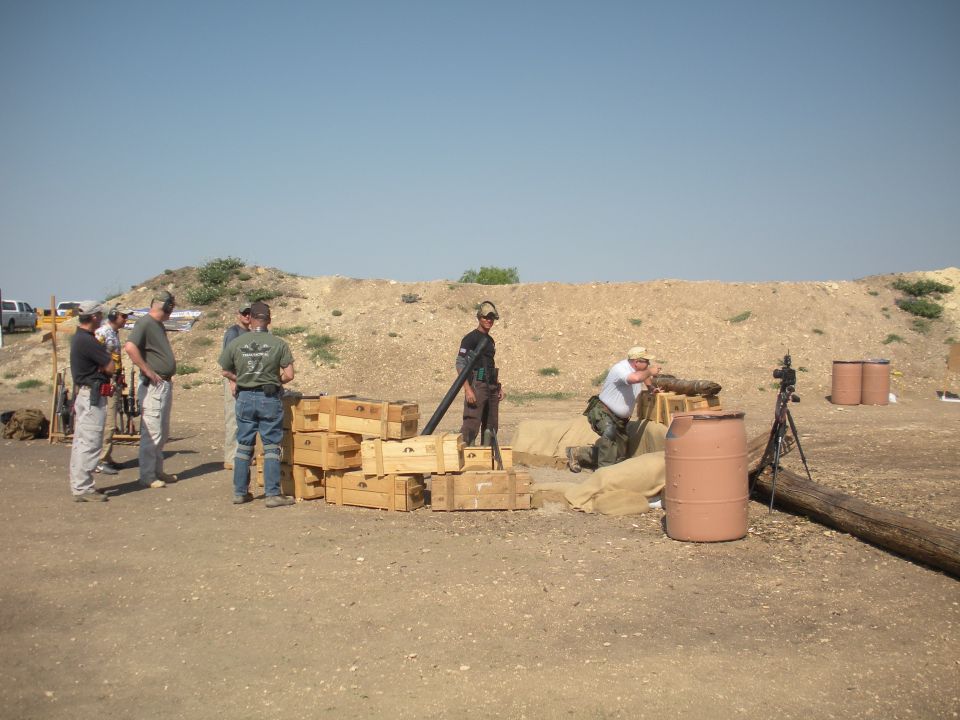 People at a shooting range with sandbags and ammunition crates