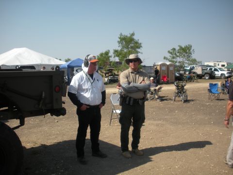 1996 Ford Bronco - Two men stand in an outdoor area with tents and various vehicles visible in the background under a clear sky.