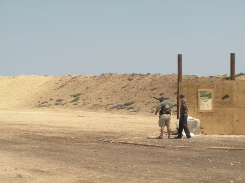 1996 Ford Bronco - Two men are at an outdoor shooting range with a dirt berm and wooden structures.
