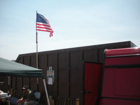 1996 Ford Bronco - American flag flies against a clear sky, with a dark structure and red trailer in the background.