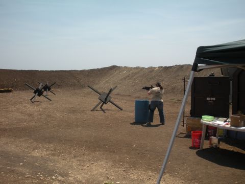 1996 Ford Bronco - A person practices shooting at a range with various obstacles and a tent in the background.
